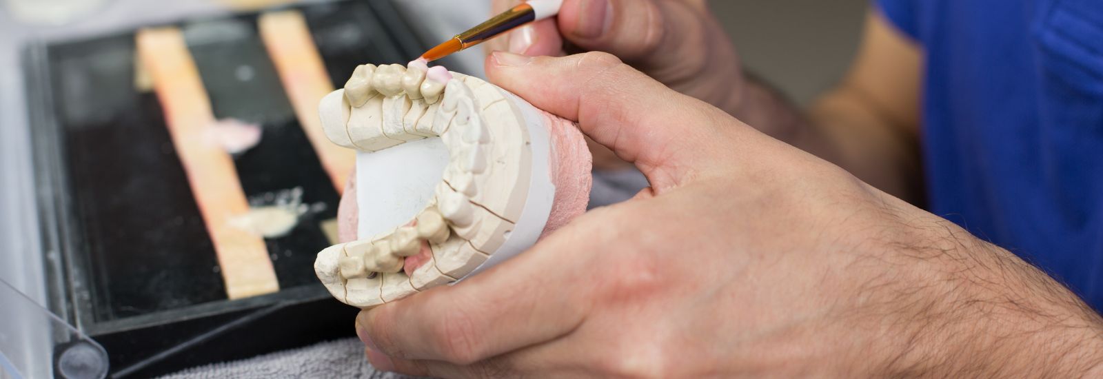 Dental technician applying porcelain to a mold